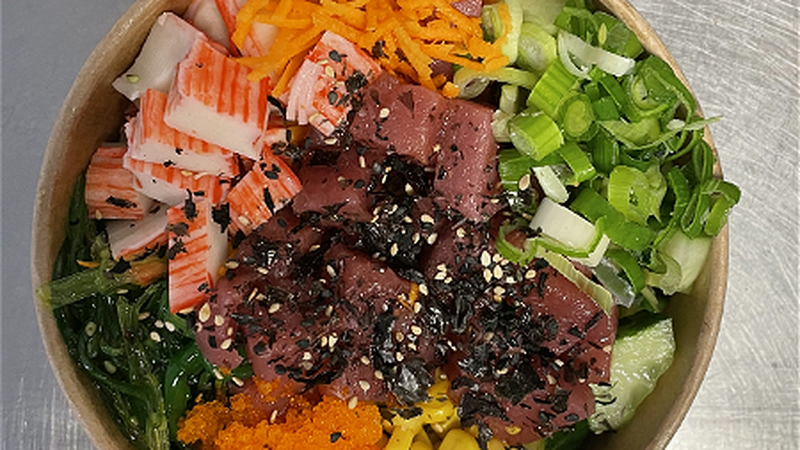 Een poke bowl van Poké Planet met tuna, krab, zeewiersalade, mais en lente-ui.